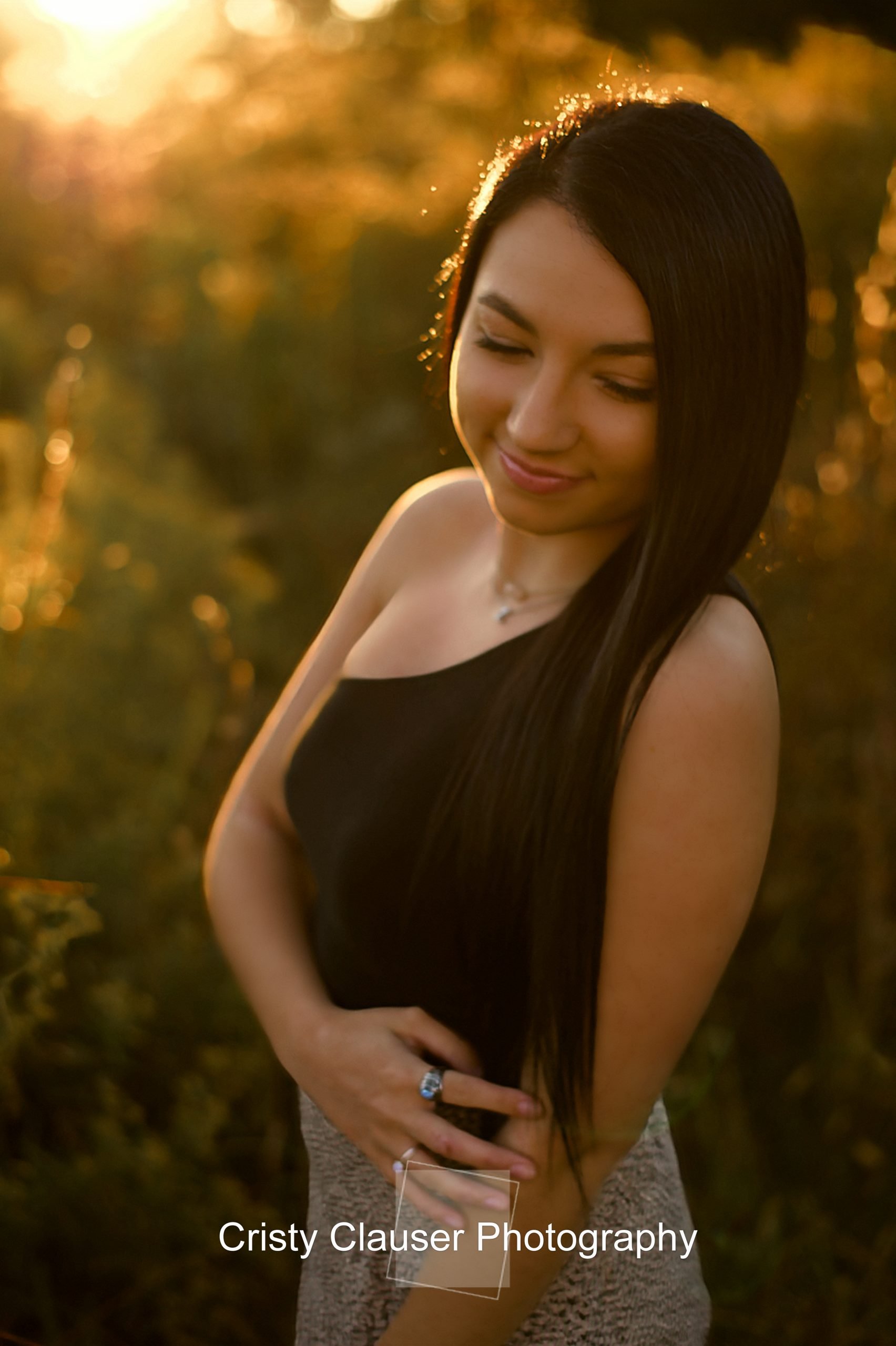 A gentle smile graces the face of a student in their portrait, as the late day sun bathes them, with a gently blurred background.