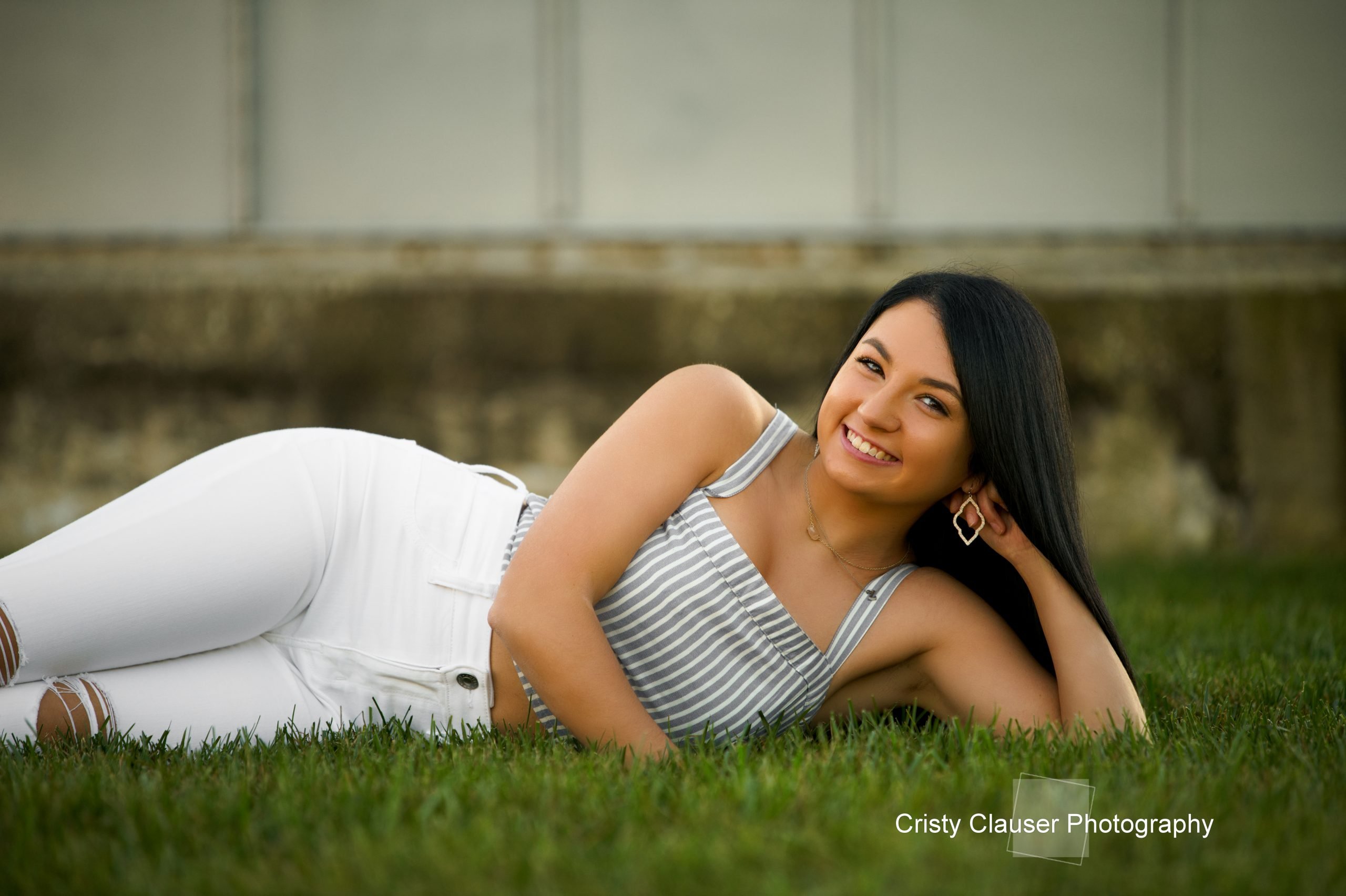 A girl laying in a field, wearing a smile that captures the happiness of her senior year