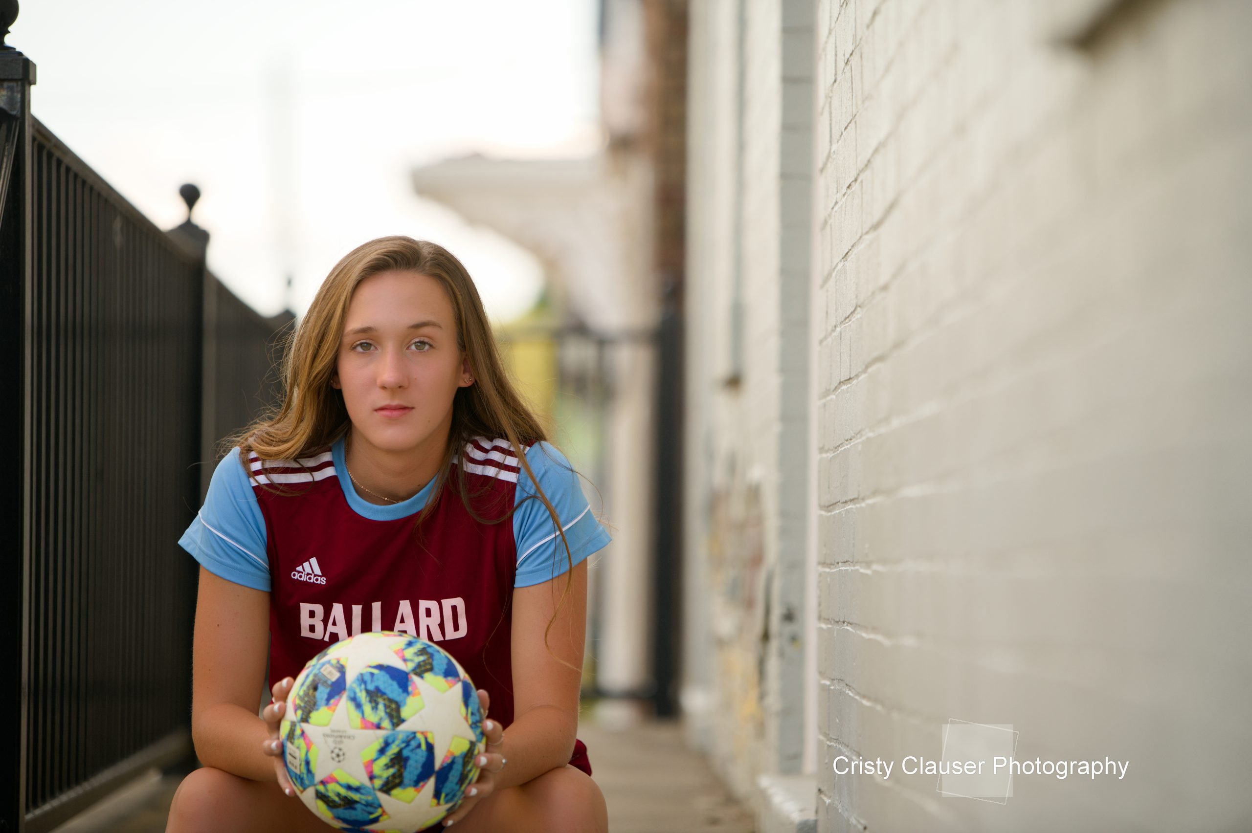 A focused expression on a student's face in a school uniform, holding a soccer ball, with a gently blurred background